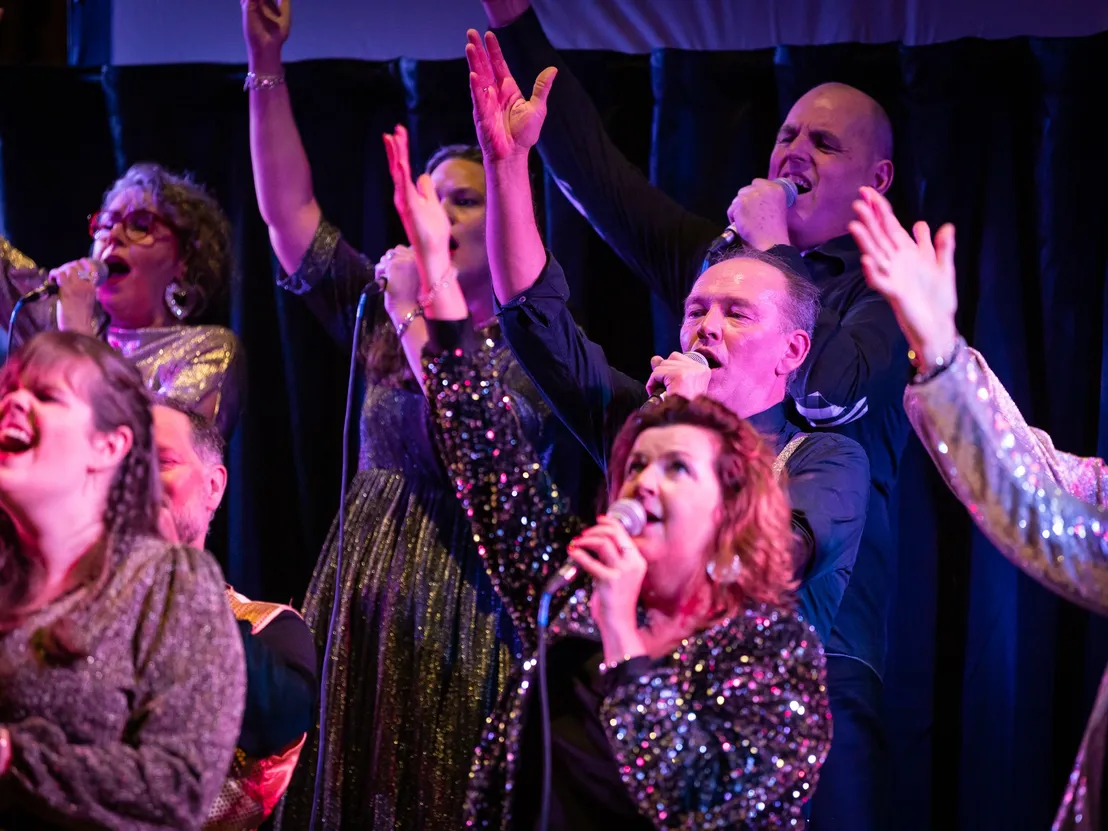koor zingt gepassioneerd met handen omhoog