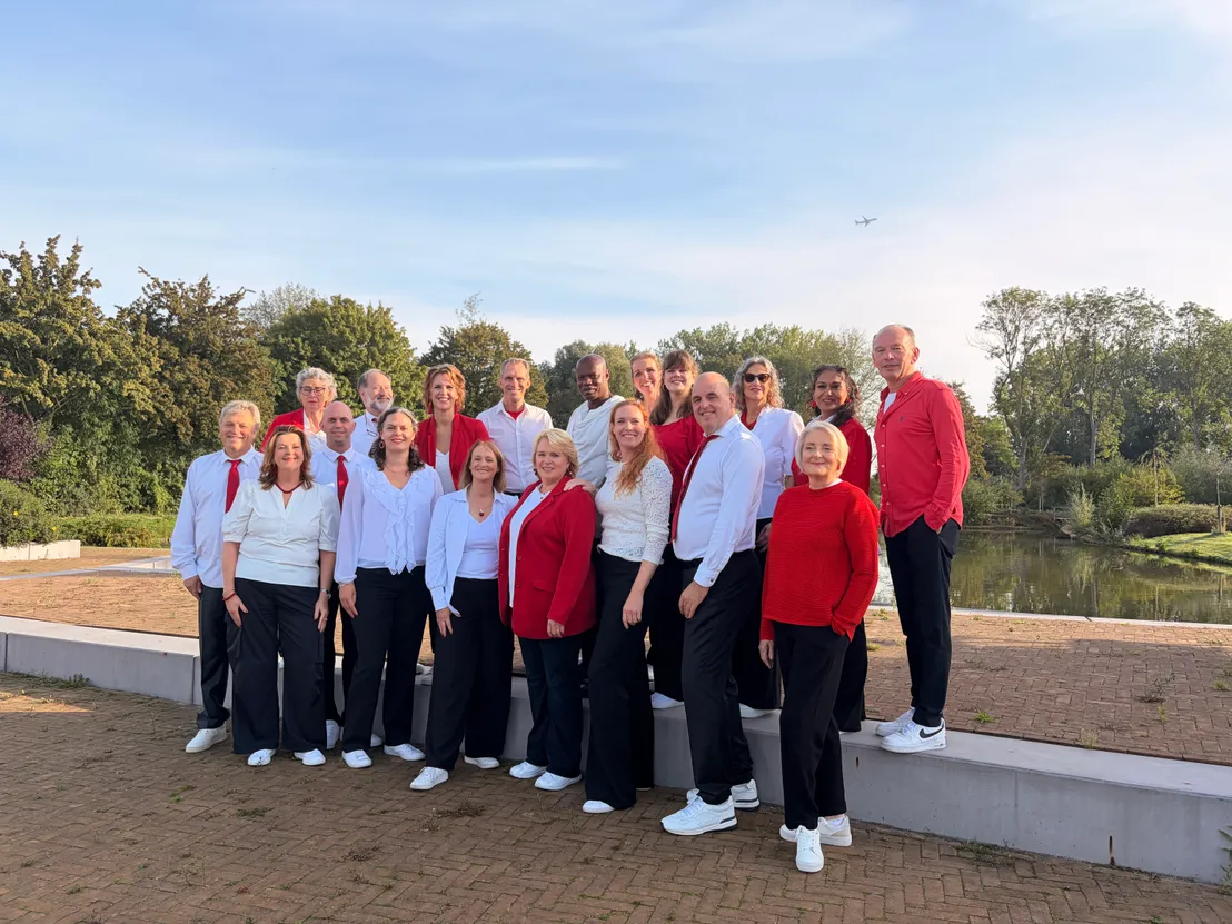 Het koor staat buiten te poseren in rood witte kleding