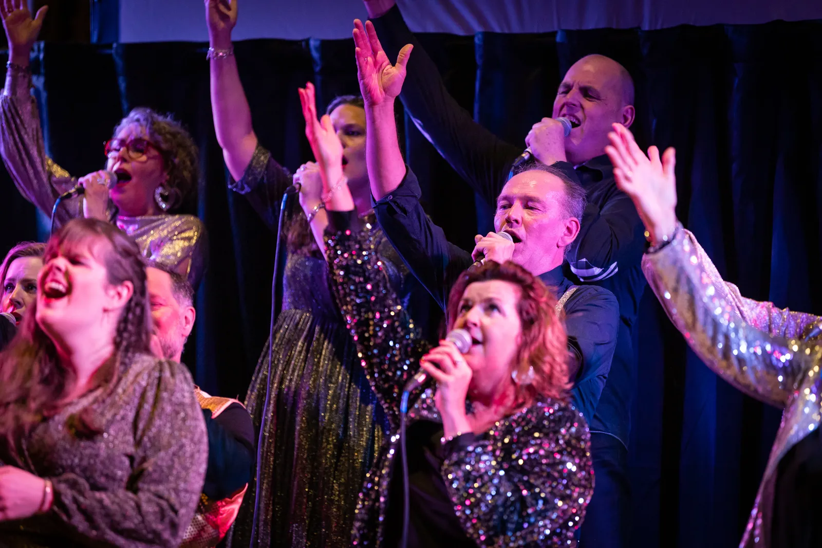 koor zingt gepassioneerd met handen omhoog